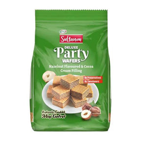 A green bag of Sultanm Deluxe Party Wafers Hazelnut Flavoured & Cocoa Cream Filling, featuring a photo of stacked wafers on a white plate with hazelnuts, set against a plain white background.