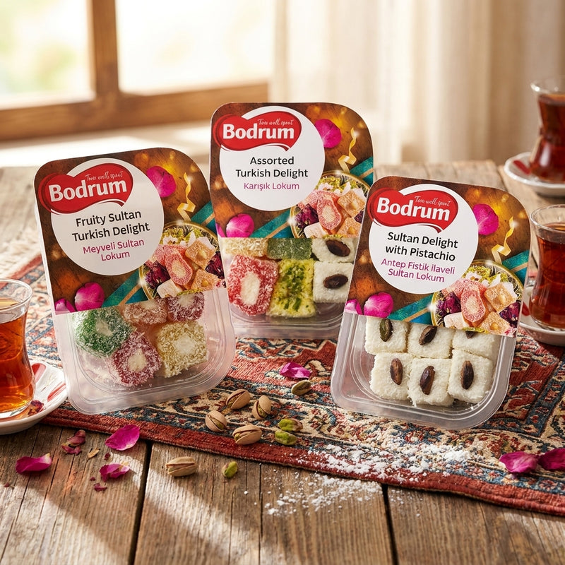 Three packages of Bodrum Turkish Delight on a wooden table with tea and rose petals.